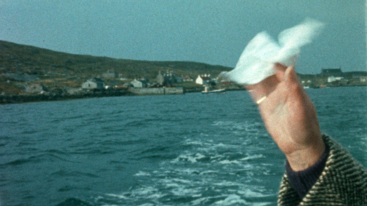Picture from the 1960s shows a woman's hand waving a hankie. She is on a ferry leaving the Island of Berneray.