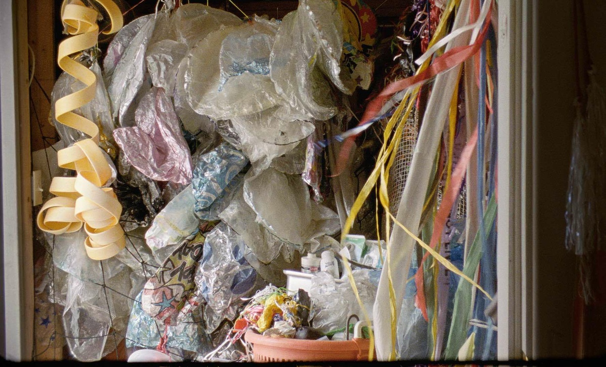 A cupboard stuffed with faded old plastic waste, sorted into different types: plastic bags and balloon strings.