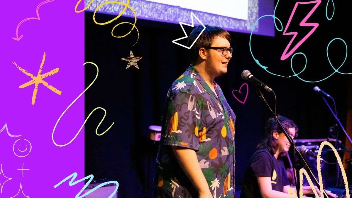A person in a colourful shirt on stage singing into a microphone, there are bright graphics scribbled across the photo