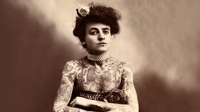 A old black and white photo of a woman covered in tattoos.