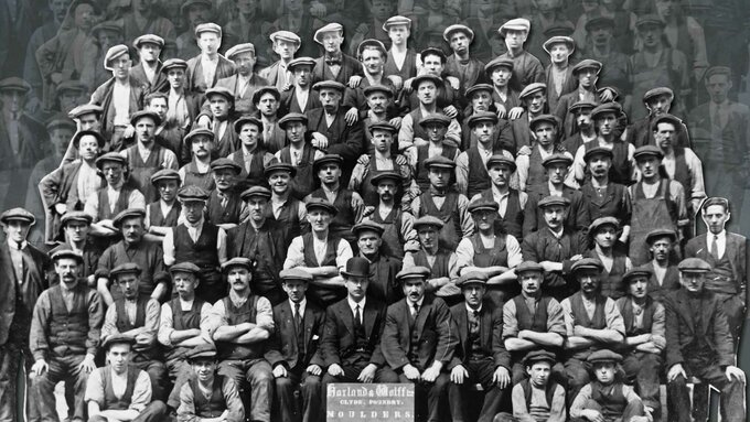 Black and white image of rows of male workers. They are wearing hats, waistcoats or jackets and white shirts.