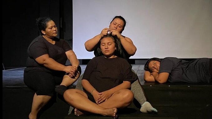4 brown skinned women of various ages sat on a stage, interacting casually but intimately.