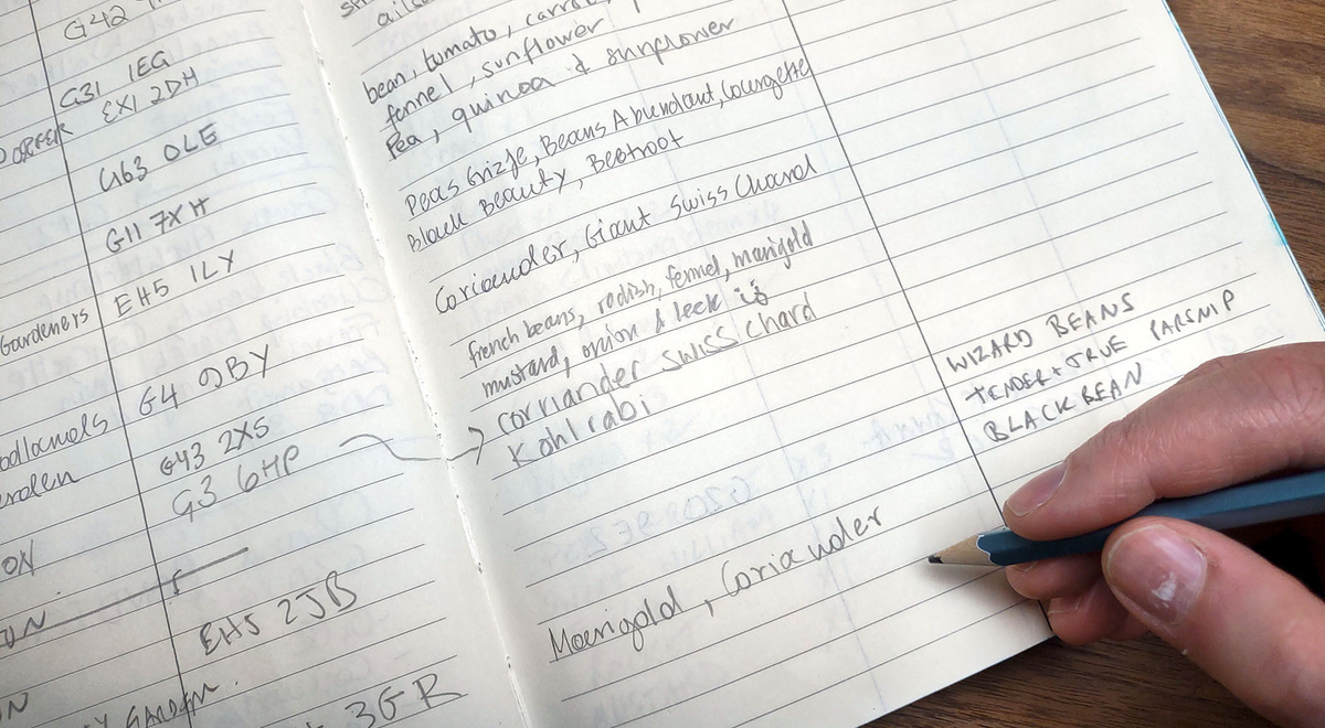 A hand writing in the seed library log book.