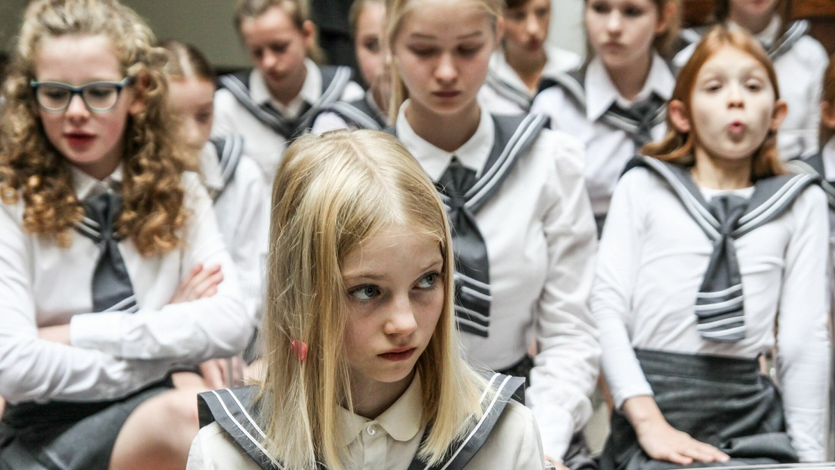 A group of students during assembly; one of the girls has chewing gum in her hair.