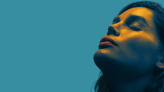 A woman's face staring serenely up wards on a blue background.