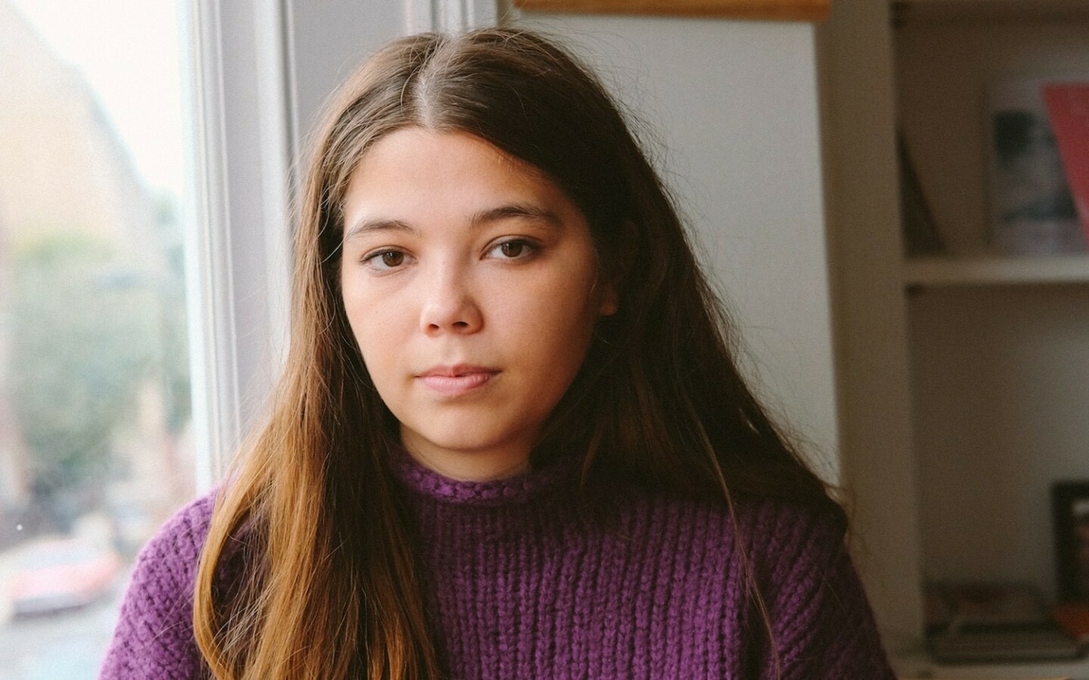 Nina Mingya Powells, standing indoors wearing a violet jumper