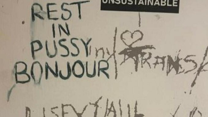 A bathroom wall with graffiti that reads 'Rest in Pussy Bonjour'