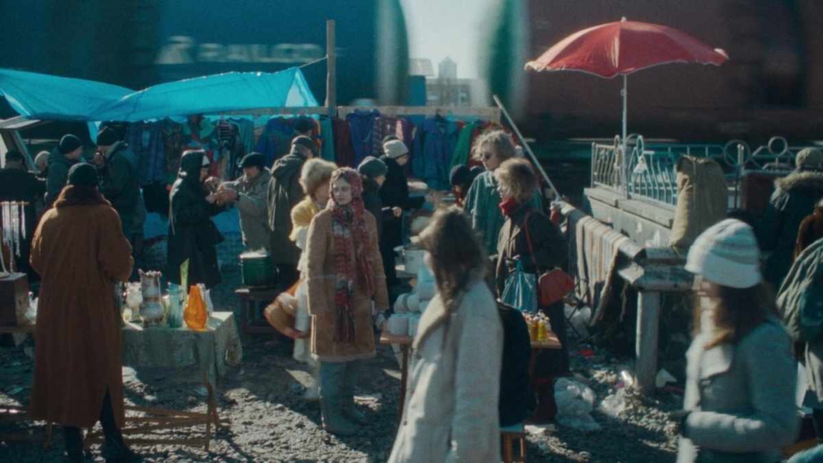 A young woman wrapped in warm clothes at a cold outdoor market.