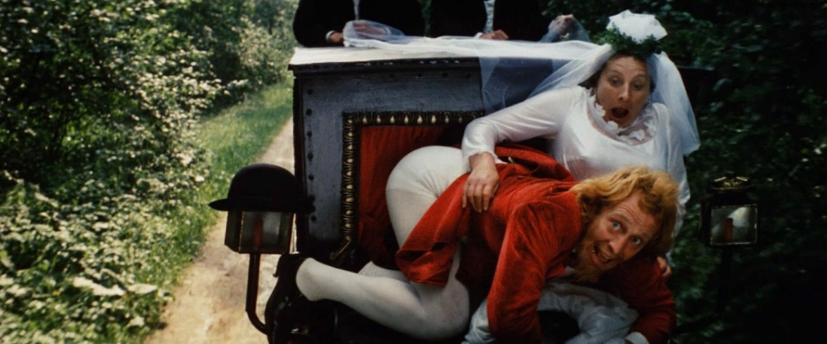 A comic scene between a man in a red velvet tunic and stockings on the lap of a woman in a wedding dress.