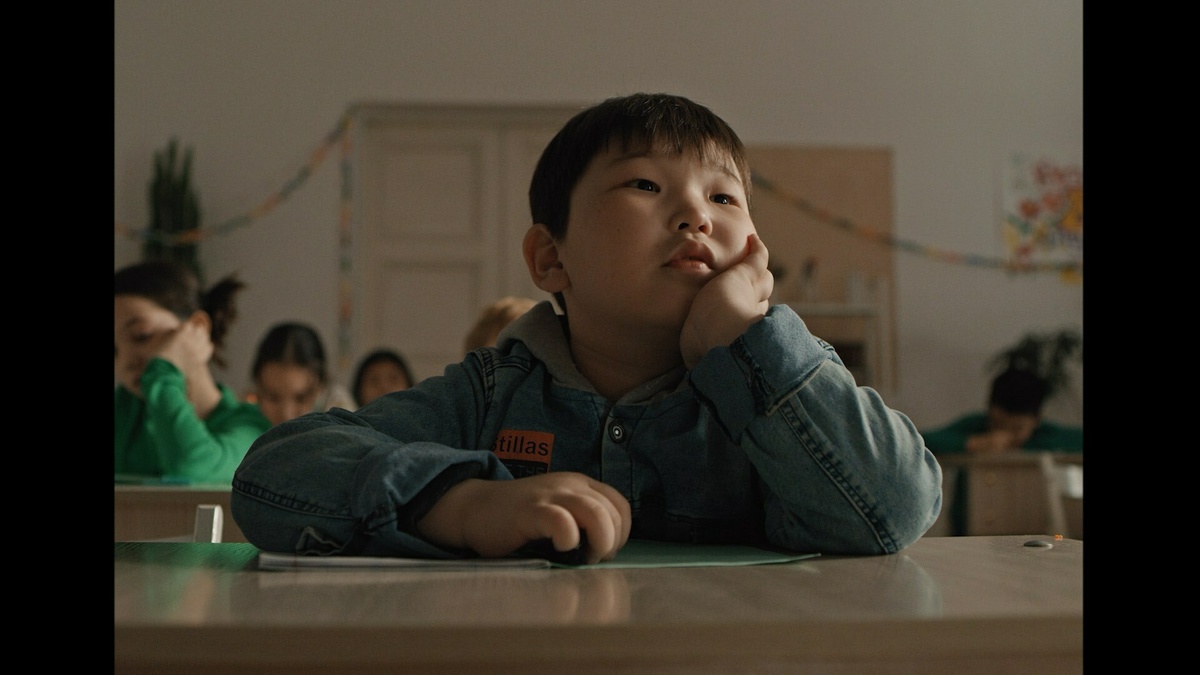 A young Kazakh boy at school, daydreaming and staring into the distance.