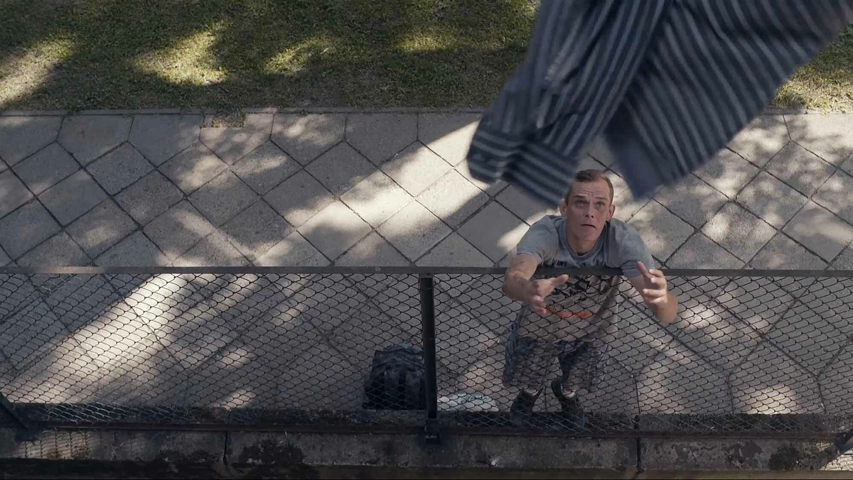 A man catching a striped blue shirt thrown down from the balcony.