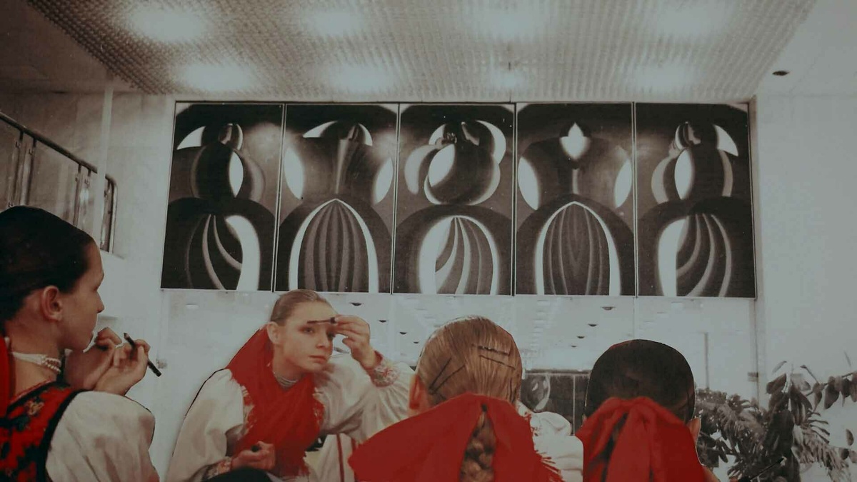 A group of women wearing traditional outfits applying makeup.