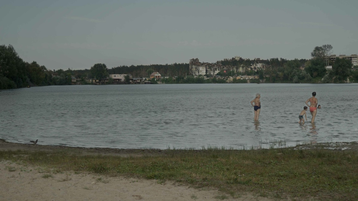 A serene lake with a group of people paddling in it and a cityscape in the distance.