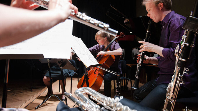 An image of flautists, cellists, and clarinet players performing together.