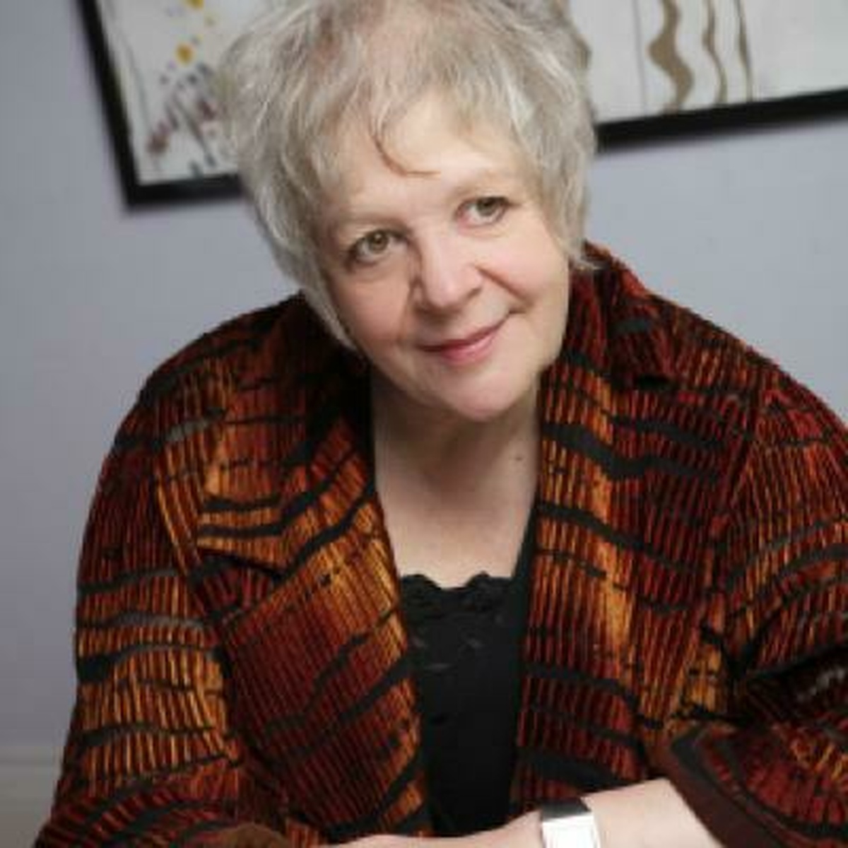 An older woman with short white hair wearing a tiger striped blazer.