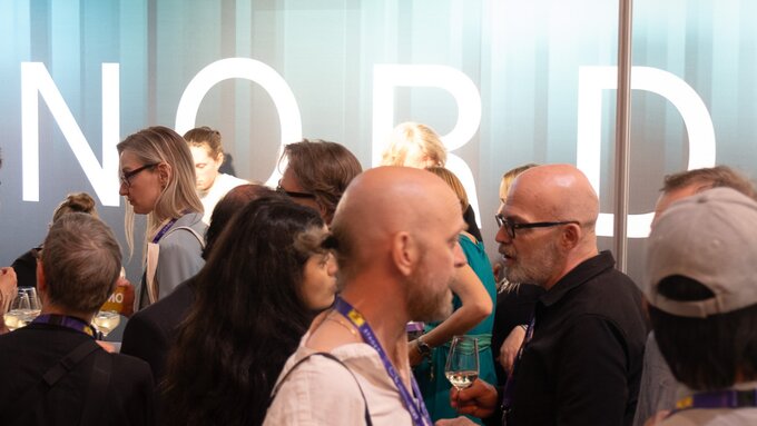 A crowd of people gathered in front of a sign that reads "Nord".