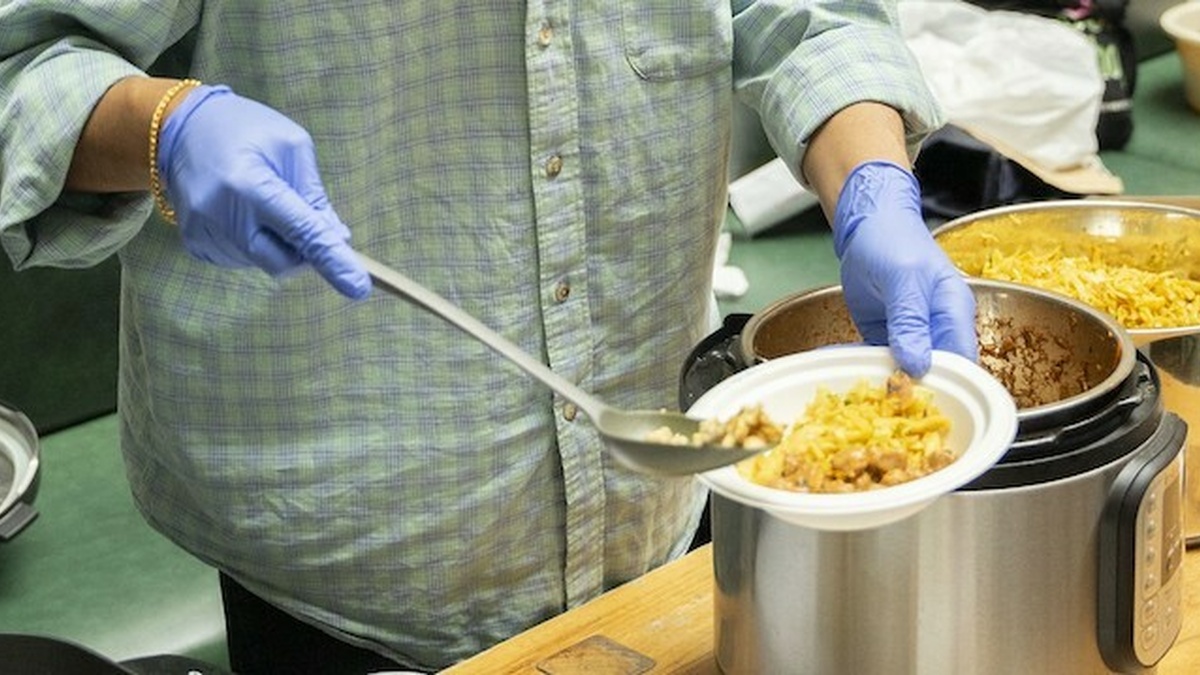 A person scoops food from a large pot.