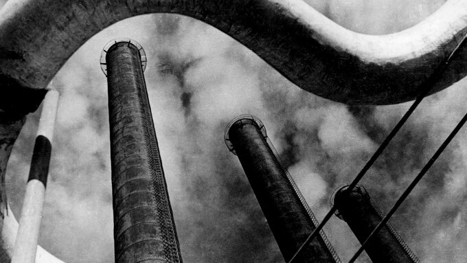 Large chimneys stretch towards a foggy sky.