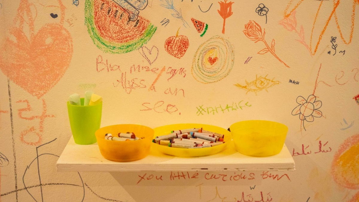 A white wall with lots of brightly coloured doodles drawn on it.