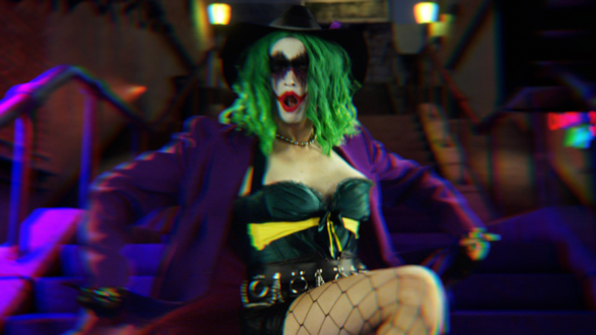 The Joker, a woman dressed in fishnets, corset and a purple jacket, dances joyfully on a set of outside stairs.