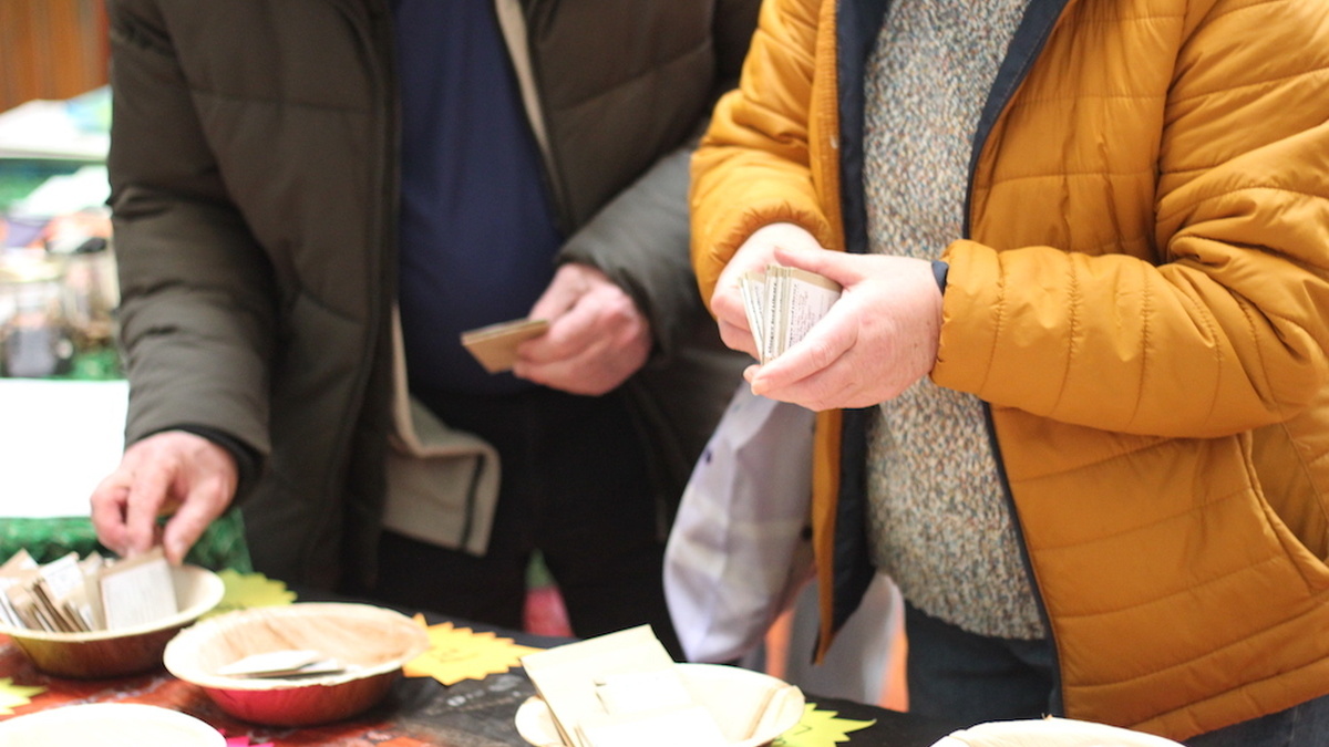 Two people wearing jackets rummaging through seed packets.