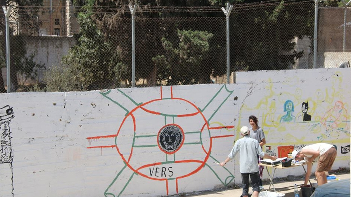 A white wall in Palestine being painted by members of the International Academy of Art Palestine.