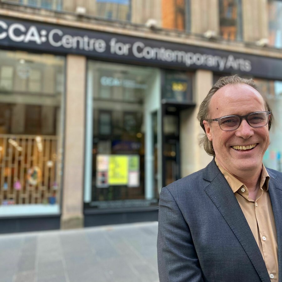 An older man in a suit stood in front of the CCA and smiling.